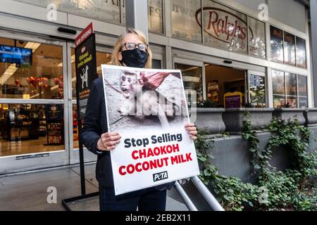 Los Angeles, États-Unis. 11 février 2021. L'activiste du PETA tient un écriteau lors d'une manifestation contre la marque Chakoh en Thaïlande pour avoir soi-disant forcé des singes à grimper sur des arbres pour collecter des noix de coco et les garder dans des conditions cruelles. Les principaux détaillants américains, comme Costco et Target, ont cessé de vendre du lait de coco Chaokoh en raison d'allégations de travail forcé des singes. Crédit : SOPA Images Limited/Alamy Live News Banque D'Images