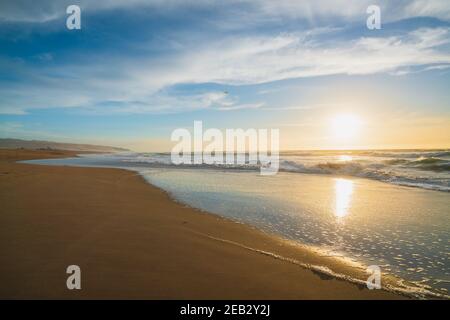 Coucher de soleil sur la plage. Belle scène tranquille de plage de sable vide, eau turquoise, et ciel nuageux Banque D'Images