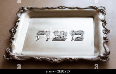 Un plateau d'argent avec le mot matzah écrit dessus en hébreu, conçu pour matzah, qui est un pain spécial pour la Pâque Banque D'Images