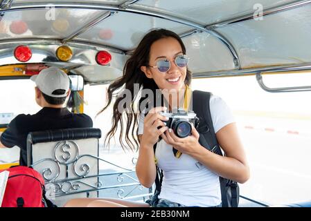 Bonne souriante femme asiatique touriste routard tenant la caméra pendant la conduite Un véhicule tuk tuk à Bangkok en Thaïlande Banque D'Images