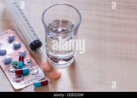 Fermez la seringue et les comprimés avec des comprimés sur une table en bois. Concept de santé et de médecine Banque D'Images