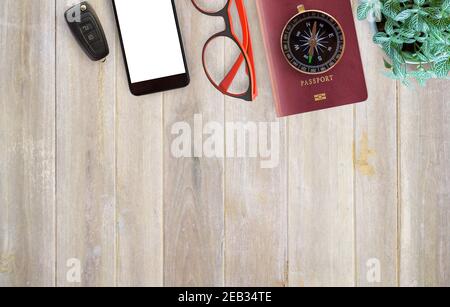 Bureau table avec matériel de bureau, ordinateur portable, smartphone, clé de voiture, passeport, boussole et fleur sur fond de table en bois. Vue de dessus avec co Banque D'Images