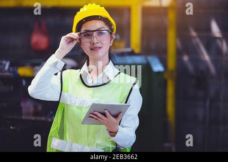 Usine industrielle de femmes avec une tablette en main, ingénieur cherchant à travailler à la configuration de machines industrielles en usine. Banque D'Images
