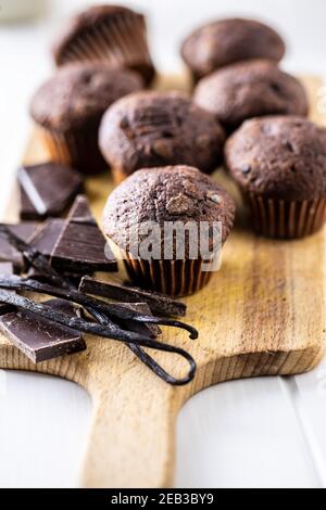 Muffins au chocolat. Petits gâteaux doux et foncés avec gousses de chocolat et de vanille sur planche à découper. Banque D'Images