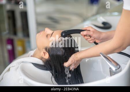 La styliste de cheveux rince les cheveux à sa cliente dans un cheveu salon Banque D'Images