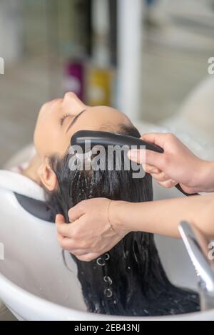 La styliste de cheveux rince les cheveux à sa cliente dans un cheveu salon Banque D'Images