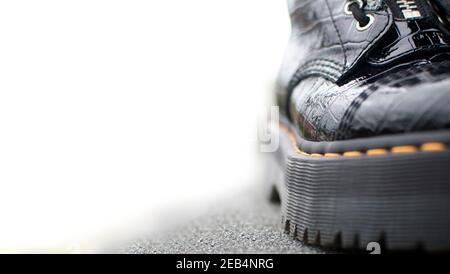 Vue avant d'une partie d'une chaussure noire brillante avec semelle en caoutchouc haute et lacets. Espace pour le texte dans la zone blanche à gauche Banque D'Images