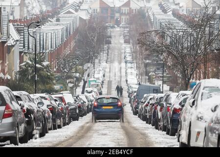 Une voiture qui descend sur une route enneigée à Crouch End, dans le nord de Londres Banque D'Images