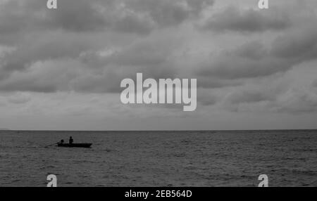 Un petit bateau courant dans la mer et le ciel avec des nuages sombres avant la tempête. Banque D'Images