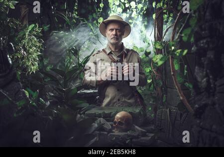 Explorateur confiant marchant dans la jungle, il se trouve à côté des ruines antiques et tient des jumelles Banque D'Images