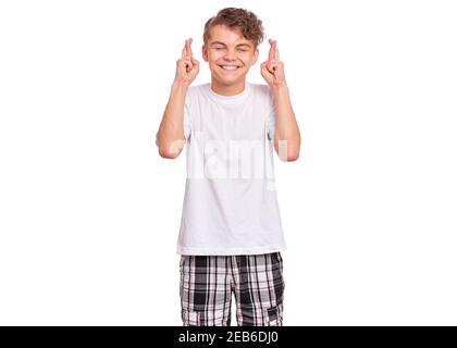 Beau garçon de l'adolescence regardant très heureux tenant les doigts croisés pour la bonne chance, isolé sur fond blanc Banque D'Images