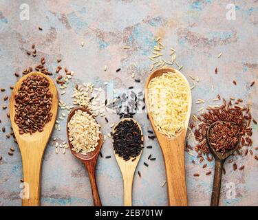 Ensemble de différents riz sur fond de béton : riz noir, basmati, brun et rouge mélangé Banque D'Images