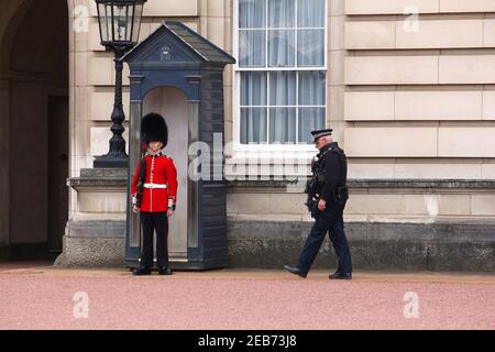 LONDRES, Royaume-Uni - 23 AVRIL 2016 : le soldat de la garde de la reine garde devant le palais de Buckingham à Londres, Royaume-Uni, accompagné d'un officier de police métropolitain. Banque D'Images