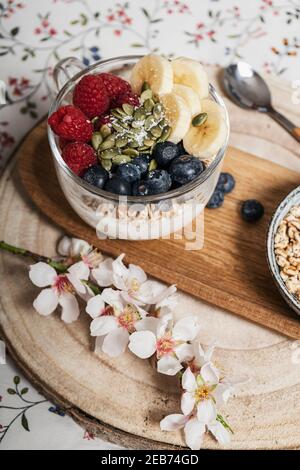 Petit-déjeuner au lit, table avec une tasse de myrtilles, bananes, framboises et yaourt Banque D'Images