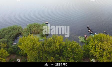 Un drone survole une rivière entourée d'un village local avec Divers bâtiments et habitats des marais et des marais avec un lit redédré De la vue aérienne de Common Reed Banque D'Images