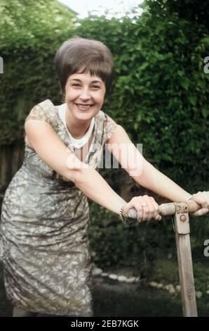 Die deutsche Schlagersängerin Renee Franke, im Garten beim Rasen mähen, Deutschland 1960 er Jahre. La chanteuse de Schlager allemand Renee Franke, la tonte d'un pré, l'Allemagne des années 1960. 24x36 swNeg39 Banque D'Images