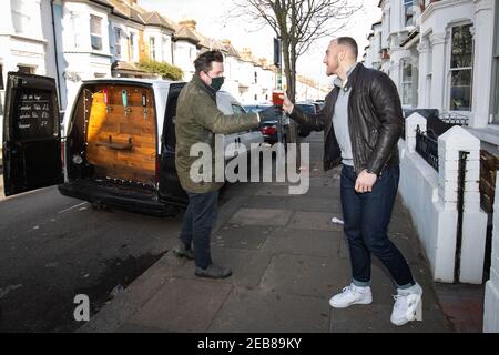 George Dean, un ancien directeur de bar, remet une pinte à un ami de son « Pub-on-Wheels » à Clapham, dans le sud de Londres. George et Finn conduisent aux portes des gens pour leur verser des pintes et créer plus d'une expérience de pub que des boîtes dans leur salon. Date de la photo : vendredi 12 février 2021. Banque D'Images