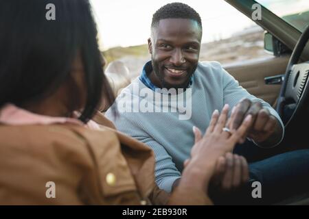 Divers couple assis dans une voiture convertible homme est la bague de mise sur la main des femmes Banque D'Images