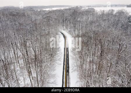 De la neige fraîche et tombée s'étend dans les arbres et sur la route de Hueston Woods, un parc d'État de l'Ohio en hiver. La route enneigée fait le tour du lac et du parc. Banque D'Images