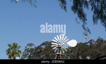 Moulin à vent rétro classique, rotor à pales et drapeau américain contre le ciel bleu. Vintage pompe à eau éolienne, générateur de puissance sur le ranch de bétail ou l'agriculture Banque D'Images