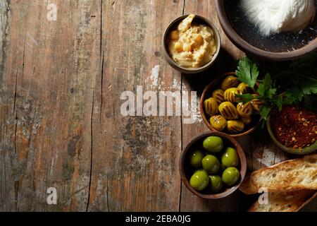 Petit déjeuner méditerranéen local avec olives vertes, baguette grillée et fromage mozzarella frais en saumure, vue depuis le plafond sur bois rustique avec Banque D'Images