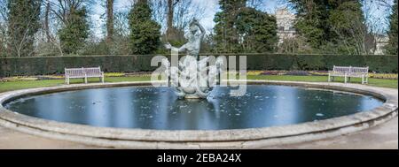 Vue panoramique d'une fontaine Triton qui est un groupe de sculptures en bronze représentant un dieu marin soufflant sur une coquille de conch avec deux mermaids à ses pieds. Banque D'Images