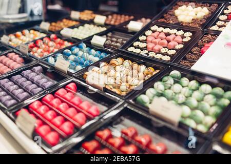 Assortiment de desserts au chocolat aux bonbons colorés sur la vitrine du café. Variété de bonbons aux saveurs différentes noix épices en magasin. Confiserie Banque D'Images