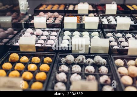 Assortiment de desserts au chocolat aux bonbons colorés sur la vitrine du café. Variété de bonbons aux saveurs différentes noix épices en magasin. Confiserie Banque D'Images