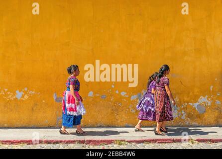 Femmes autochtones mayas guatémaltèques marchant devant une façade coloniale, Antigua, Guatemala. Banque D'Images