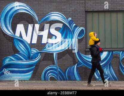 Londres, Royaume-Uni. 12 février 2021. Un homme et un enfant marchent devant une fresque du NHS dans l'est de Londres. Avec le Royaume-Uni à Lockdown, les gens ont exprimé leur admiration et leur amour pour le National Health Service. Crédit : Mark Thomas/Alay Live News Banque D'Images