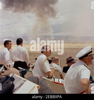 Voyage dans les États de l'Ouest : China Lake, Californie, (Naval Air Facility) NAF. Les officiers et les officiels militaires voient des démonstrations d'armes depuis leurs sièges dans le stand de révision lors de la visite du Président John F. Kennedyu0027s à l'installation aérienne navale (NAF) Chine Lacu0027s Naval Ordnance Test Station (NOTS) à China Lake, Californie; l'aide navale au Président, le Capitaine Tazewell T. Shepard, Jr., est au centre. Le chef des opérations navales, l'amiral George W. Anderson, Jr. (Portant des lunettes de soleil), et le secrétaire de la Marine, Fred Korth, siègent en première rangée. Banque D'Images