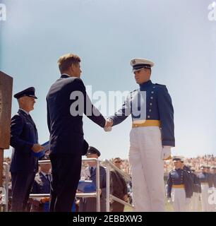 Voyage aux États de l'Ouest : le président Kennedy à l'Académie de l'US Air Force (USAF), Colorado. Le président John F. Kennedy (à gauche) tremble la main avec un cadet non identifié lors des exercices de commencement pour la cinquième classe de diplômés de l'Académie de l'US Air Force (USAF) ; le président Kennedy a prononcé un discours pour l'occasion. Également en photo : l'agent du service secret de la Maison Blanche, Emory Roberts (debout en arrière-plan au centre). Stade Falcon, USAF Academy, Colorado Springs, Colorado. Banque D'Images