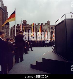 Voyage en Europe: Allemagne, Cologne: Ku00f6lner Rathaus (hôtel de ville), 10:55. Le président John F. Kennedy se rend à la plateforme Speakersu2019 avant de faire des remarques devant Ku00f6lner Rathaus (hôtel de ville) à Cologne, Allemagne de l'Ouest (République fédérale) ; le chancelier de l'Allemagne de l'Ouest, Konrad Adenauer, se promène à côté du président Kennedy. Également en photo : les agents du service secret de la Maison Blanche, Gerald A. u201cJerryu201d Behn et Sam Sullilan. Banque D'Images