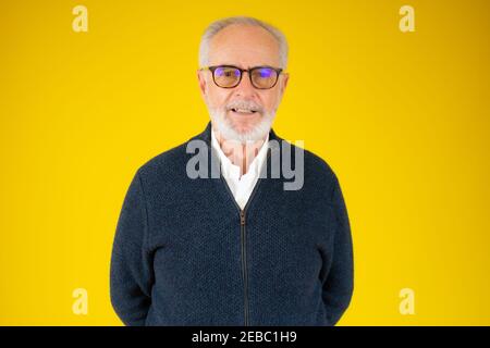 Visage de beau homme barbu senior portant une veste bleue et lunettes isolées sur fond jaune Banque D'Images