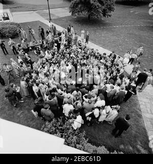 Visite des participants à l'expérience dans International Living, 12:00. Le président John F. Kennedy (vu d'en haut, dans la foule au centre à droite) visite des participants au programme expérience de vie internationale. Également en photo : Asha Mirchandani; photographe du National Park Service (NPS), Abbie Rowe; chef de la police de la Maison Blanche, Major Ralph C. u0022Smokeyu0022 Stover; correspondante de la Maison Blanche pour United Press International (UPI), Helen Thomas; photographe de cinéma pour Columbia Broadcasting System (CBS), Tom J. Craven, Jr.; photographe de presse pour United Movietone, Thomas Banque D'Images