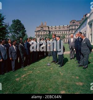 Visite des participants à l'Institut américain pour la gestion libre du travail, 10:05. Le président John F. Kennedy (à micros) fait des remarques aux participants du programme de formation de l'American Institute for Free Labor Development (AIFLD) à l'intention des dirigeants syndicaux d'Amérique latine et des Caraïbes. Le spécialiste de l'Amérique latine du département du travail des États-Unis, Joaquin A. Bazan, Jr., est à droite du président Kennedy; le participant Eric Lloyd Harris, de la Jamaïque (à l'arrière, tenant un document laminé), est au centre du groupe. Debout à l'extrême droite (L-R): Président de la Fédération américaine du travail et de la Congre Banque D'Images