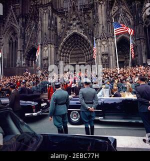 Voyage en Europe : Allemagne, Cologne : convoi, cathédrale. Le président John F. Kennedy (au centre à gauche, descendre les escaliers) quitte la cathédrale de Cologne (Ku00f6lner Dom) après avoir assisté à la messe. Le chancelier de l'Allemagne de l'Ouest, Konrad Adenauer (partiellement obscurci), avance sur le président Kennedy; le maire (Oberbu00fcrgermeister) de Cologne, Theo Bulauen, se dirige à droite du président. Kenneth P. Ou2019Donnell (de retour à la caméra), assistant spécial du président, se trouve tout à droite en premier plan. Également en photo : le directeur du Service secret des États-Unis, James J. Rowley; les agents du Service secret de la Maison Blanche, Banque D'Images