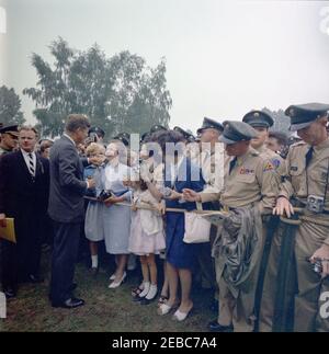 Voyage en Europe: Allemagne, Hanau: Départ de Fliegerhorst Kaserne, 14h00. Le Président John F. Kennedy (à gauche) accueille des foules rassemblées à Hanau, en Allemagne de l'Ouest (République fédérale), lors de sa visite à la base militaire de Fliegerhorst Kaserne. L'agent du service secret de la Maison Blanche, Jack Ready, se trouve à l'extrême gauche. Banque D'Images