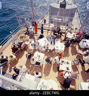 Le Président Kennedy Watches la 1ère course de la coupe Americau0027s. Le président John F. Kennedy et la première dame Jacqueline Kennedy assistent à la première course de la coupe Americau0027s 1962 à bord de l'USS Joseph P. Kennedy, Jr., au large de Newport, Rhode Island. Le Président Kennedy (assis à gauche, regardant à travers des jumelles) regarde la course; Mme Kennedy (en bas à gauche) visite le Chef du Protocole, Angier Biddle Duke. Également en photo : John Forbes Kerry; Janet Jennings Auchinclors; Franklin D. Roosevelt, Jr.; Nuala Pell, épouse du sénateur Claiborne Pell (Rhode Island); Julia Ann Shepard; sénateur John Sherman Co Banque D'Images