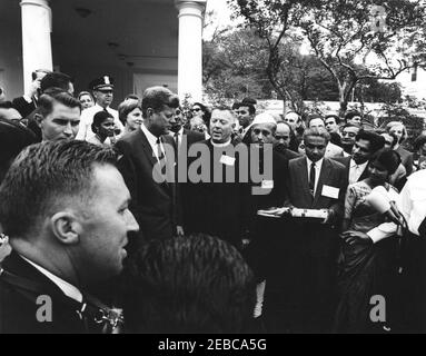 Visite des participants à l'expérience dans International Living, 12:00. Le Président John F. Kennedy (centre gauche) visite des participants au programme expérience de vie internationale. Asha Mirchandani, de l'Inde (qui a présenté au président Kennedy une photo en marbre de la première dame Jacqueline Kennedy), est deuxième à droite du président Kennedy; d'autres sont non identifiés. Également en photo : Chef de la police de la Maison Blanche, Major Ralph C. u0022Smokeyu0022 Stover; Agent du Service secret de la Maison Blanche, Toby Chandler. West Wing Lawn, Maison Blanche, Washington, D.C. Banque D'Images