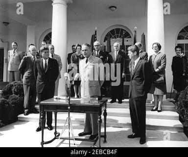 Cérémonie d'assermentation, général Maxwell Taylor, Président, JCS, 12 h 00. Le général Maxwell D. Taylor (au centre, à micros) fait des remarques lors de sa cérémonie d'assermentation en tant que président des chefs d'état-major interarmées (JCS); le président John F. Kennedy (à gauche) et le procureur général Robert F. Kennedy, se tiennent de part et d'autre du général Taylor. En regardant les marches de la Colonnade de l'aile Ouest, en commençant tout à l'arrière (de gauche à droite): Aide militaire au président, le général Chester V. Clifton; le général Omar Bradley; aide aérienne au président, le général de brigade Godfrey T. McHugh (pour la plupart caché); Naval Banque D'Images