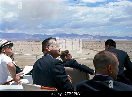 Voyage dans les États de l'Ouest : China Lake, Californie, (Naval Air Facility) NAF. Le président John F. Kennedy (au centre, portant des lunettes de soleil) voit des démonstrations d'armes depuis son siège dans le stand d'examen lors de sa visite à la Naval Air Facility (NAF) China Lakeu0027s Naval Ordnance Test Station (NOTS) à China Lake, Californie. Le secrétaire de la Marine, Fred Korth, est assis dans la première rangée du stand de revue à l'extrême gauche; l'agent du Service secret de la Maison Blanche, Gerald A. u0022Jerryu0022 Behn (portant des lunettes de soleil) est assis au centre. Banque D'Images