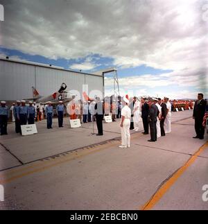 Voyage dans les États de l'Ouest : China Lake, Californie, (Naval Air Facility) NAF. Le président John F. Kennedy (au centre, à microphone) s'adresse aux pilotes et aux marins à la suite de démonstrations d'armes à la Naval Air Facility (NAF) China Lakeu0027s Naval Ordnance Test Station (NOTS) à China Lake, en Californie; Pilote dans la démonstration de canon externe haute performance (HIPEG), le lieutenant David F. Callahan, Jr. (Portant une combinaison orange et un casque de maintien), se tient près du centre gauche. Parmi les personnes qui se tiennent en groupe derrière le Président Kennedy, citons : le Secrétaire de la Marine, Fred Korth; l'aide navale au Président, le capitaine Tazew Banque D'Images