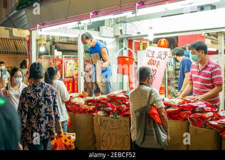 Les gens portant le masque facial comme précaution contre la propagation de la marche de covid-19 devant un stand de traite du nouvel an chinois à Chinatown à la veille du nouvel an lunaire.Singapour est entré dans la phase 3 le 28 décembre 2020, permettant aux personnes de groupes de 8 à se rencontrer pour des rassemblements sociaux. Banque D'Images