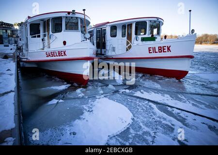 Hambourg, Allemagne. 12 février 2021. Les cuiseurs à vapeur Alster exploités par Alster-Touristik sont entourés de flotteurs de glace à leur jetée sur Jungfernstieg dans le Binnenalster. La couverture de glace des étangs et des lacs de Hambourg et du Schleswig-Holstein est encore mince malgré quelques jours de gel. Les autorités continuent de mettre en garde contre la marche sur la glace dans les eaux. (À dpa 'beau temps d'hiver au-dessus de Hambourg et Schleswig-Holstein') Credit: Christian Charisius/dpa/Alamy Live News Banque D'Images