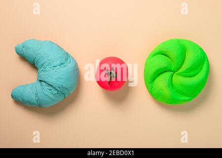 Des couleurs originales. Croissant bleu, tomate rose fluo et pain vert fluo. Concept minimal de Flat Lay Banque D'Images