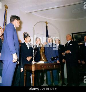 Présentation du Trophée international Harmon 1961 pour aviateurs, 12:00. Le président John F. Kennedy se penche sur William E. Schramek, membre du conseil d'administration du Harmon International Trophy, qui lit les citations de la présentation du Harmon International Trophy 1961 pour aviateurs. (G-D) homme non identifié, président Kennedy, A. Scott Crossfield, Joseph A. Walker, major Alexander P. de Seversky (partiellement caché), major Robert M. White, colonel Ansel E. Talbert, William E. Schramek, homme non identifié. Fish Room, Maison Blanche, Washington, D.C. Banque D'Images