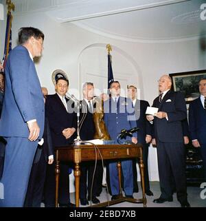 Présentation du Trophée international Harmon 1961 pour aviateurs, 12:00. Le président John F. Kennedy se penche sur William E. Schramek, membre du conseil d'administration du Harmon International Trophy, qui lit les citations de la présentation du Harmon International Trophy 1961 pour aviateurs. (G-D) le président Kennedy, A. Scott Crossfield, Joseph A. Walker, le major Alexander P. de Seversky (partiellement caché), le major Robert M. White, le colonel Ansel E. Talbert, William E. Schramek, homme non identifié. Fish Room, Maison Blanche, Washington, D.C. Banque D'Images