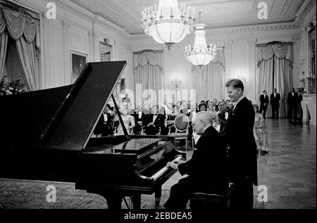 Dîner en l'honneur de l'ancien président Harry S. Truman (TVH), 8 h 00. L'ancien président Harry S. Truman joue du piano lors d'un dîner en son honneur. Le pianiste Eugene List est derrière le président Truman. Assis, Front Row (G-D): Le congressiste Richard W. Bolling (Missouri), l'ancienne première dame Bess Truman, le président John F. Kennedy, la première dame Jacqueline Kennedy et le vice-président Lyndon B. Johnson. La photographie comprend également l'ancien sénateur Scott W. Lucas (Illinois), Roberta Vinson, Lady Bird Johnson et le conseiller présidentiel Clark M. Clifford. East Room, White House, Washington, D.C. Banque D'Images