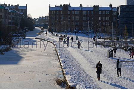 Édimbourg, Écosse, Royaume-Uni. 12 février 2021. Les gens apprécient un après-midi froid ensoleillé mais glacial le long du canal Union au bassin de Lochrin, avec le canal gelé solide avec de la glace. Crédit : Craig Brown/Alay Live News Banque D'Images